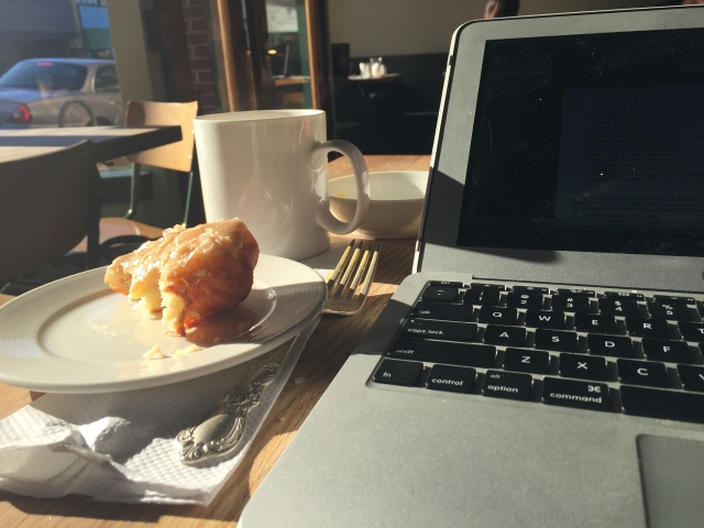 laptop and apple fritter at a cafe